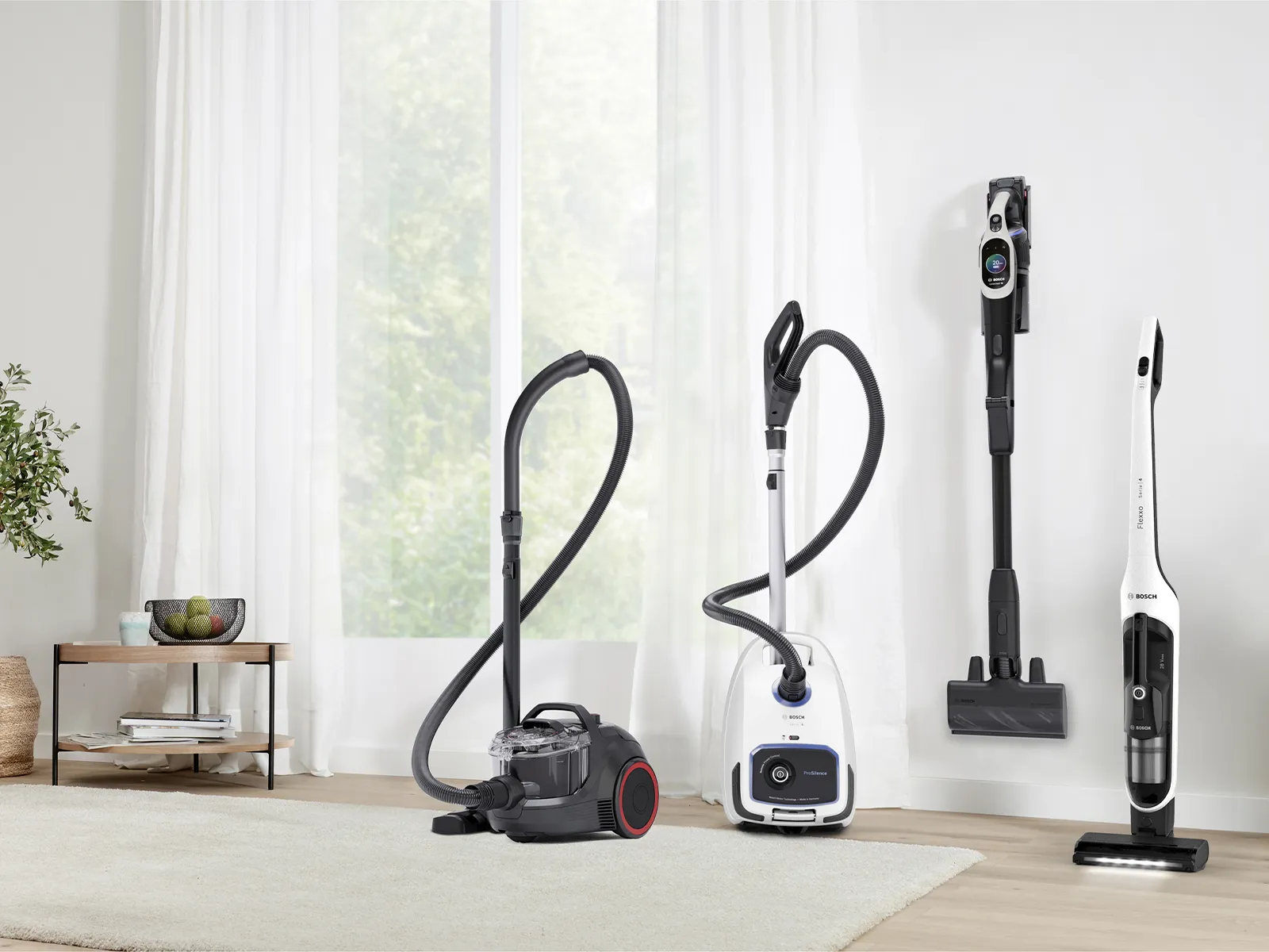 Vier verschiedene Staubsaugertypen in einem hellen Raum ausgestellt.