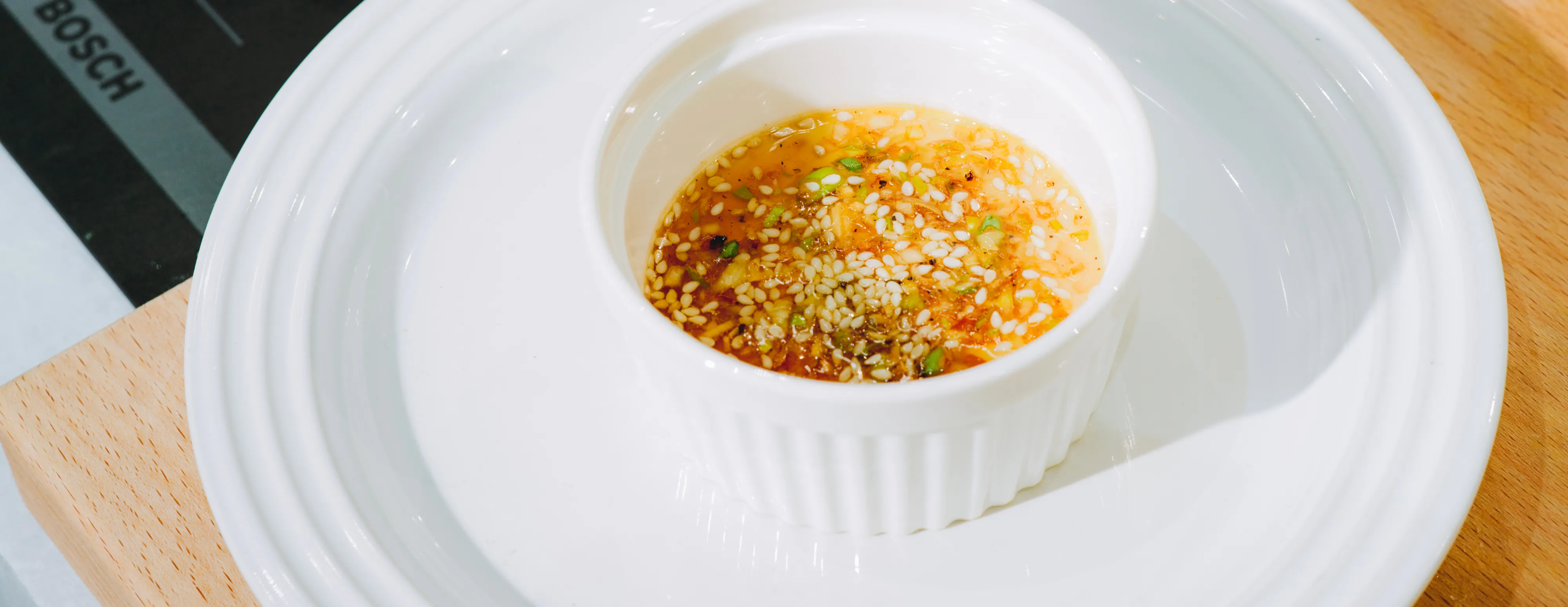 Steamed egg with sesame and spice mixture on a wooden surface and a Bosch label visible.