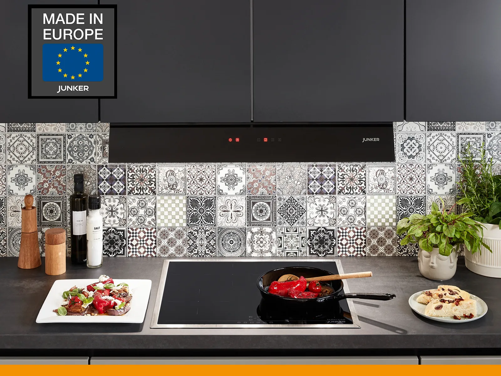 Moderne Junker-Küche mit einer stilvollen Rückwand, Kochutensilien und bunten Tellern, mit einem gut sichtbaren "Made in Europe"-Etikett.