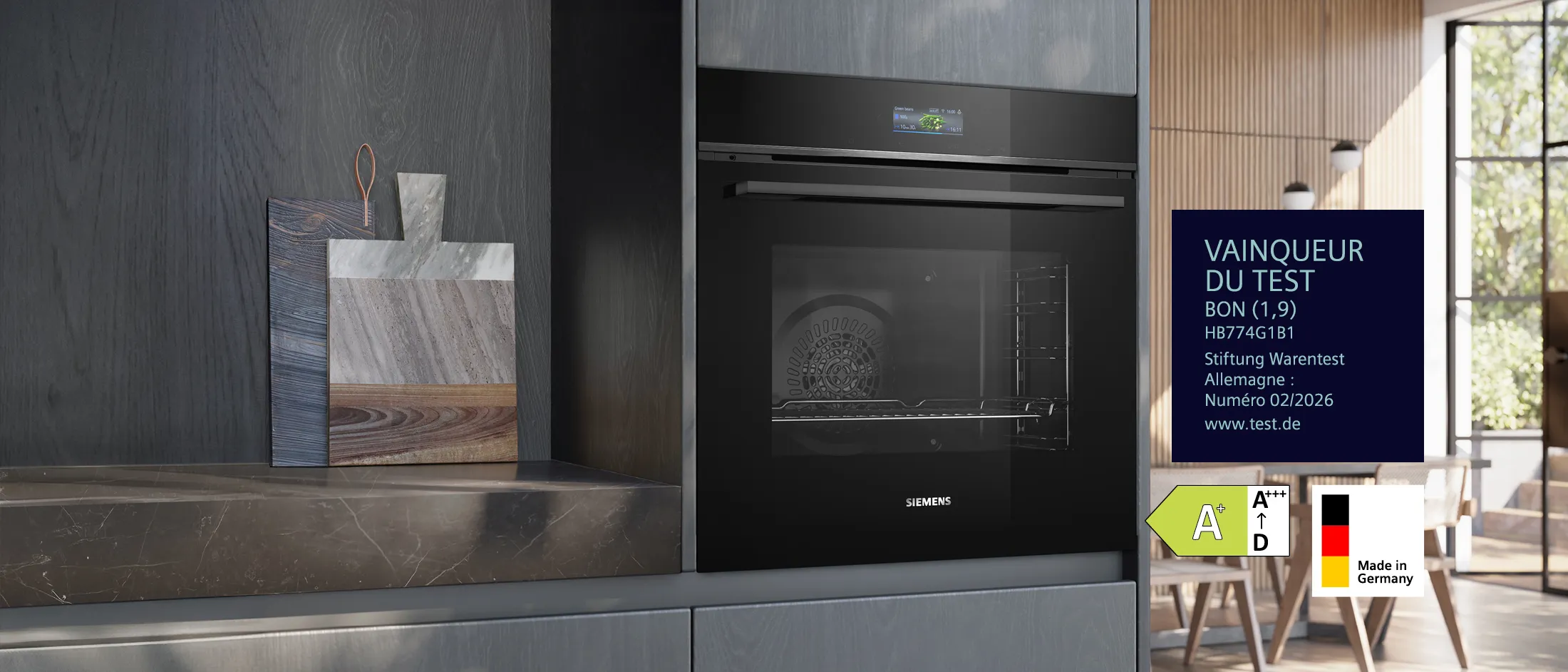 Un four encastrable noir Siemens, modèle HB774G1B1, dans une cuisine moderne. L'image met en avant le label "Testsieger" (vainqueur du test) de Stiftung Warentest avec la note "GUT (1,9)" (BIEN), l'étiquette énergétique A+ et le label "Made in Germany".