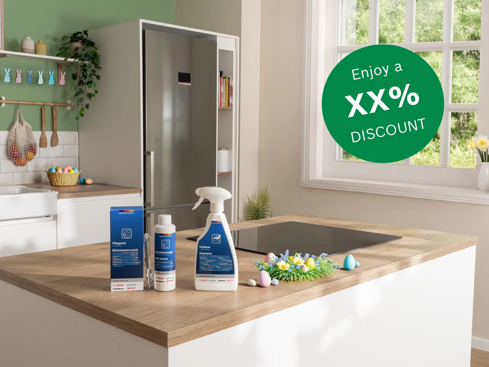 Bright kitchen island with blue cleaning bottles and spray, induction cooktop, Easter eggs and flower wreath, sink, fridge and sunlit window daffodils