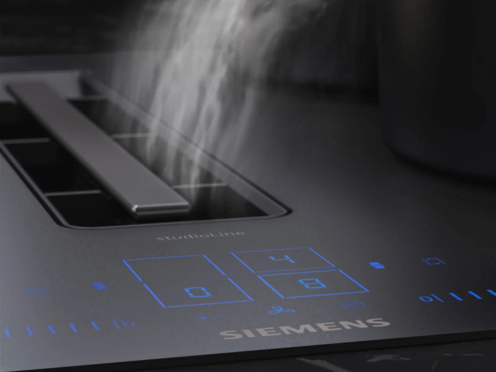 A Siemens studioLine induction hob with an active downdraft extractor fan pulling steam, demonstrating the climateControl Sensor.