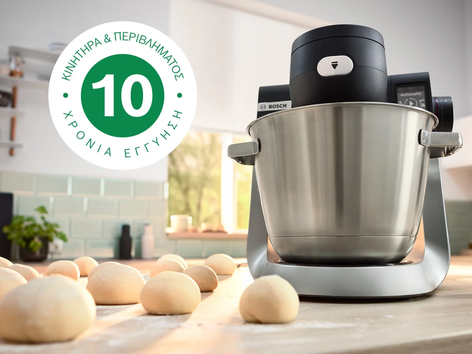 Εικόνα που δείχνει την κουζινομηχανή Σειρά 6 πάνω στον πάγκο μιας κουζίνας, δίπλα σε πολλά μπαλάκια ζύμης και το λογότυπο της 10ετούς εγγύησης.