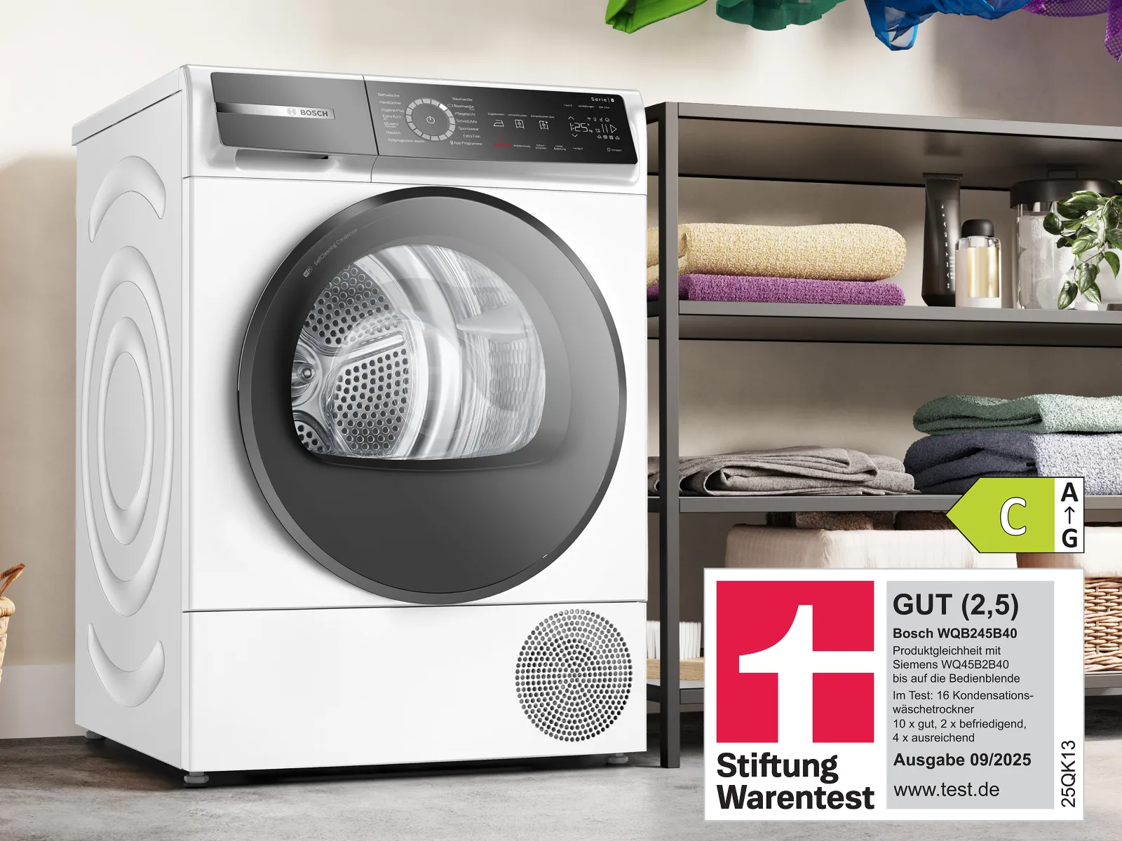 Ein moderner weißer Trockner mit transparenter Tür steht neben ordentlich gefalteten Handtüchern auf einem Regal und zeigt ein Energieeffizienzlabel.