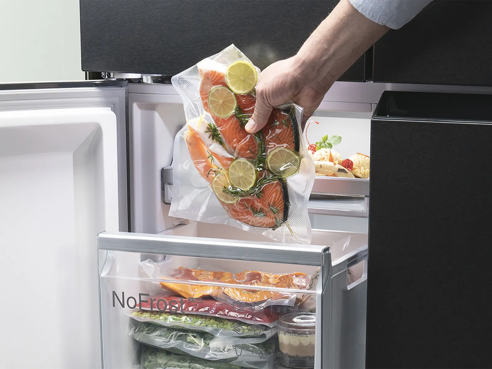 Hand placing vacuum-sealed salmon into a freezer drawer.