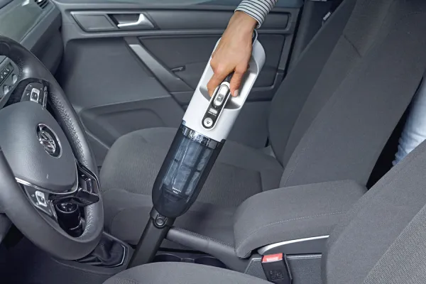 Person using 2in1 vacuum to vacuum between seats