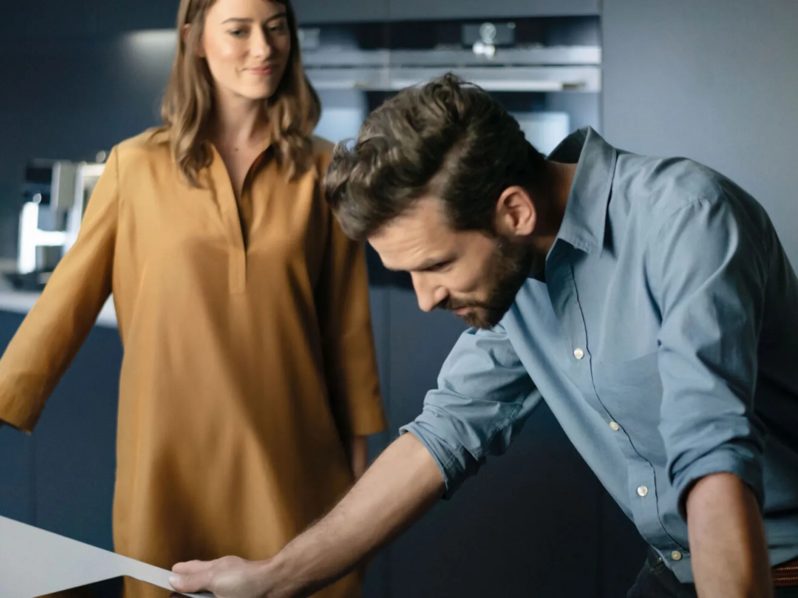 Un homme penché au-dessus d'une plaque à induction Siemens et une femme debout en arrière-plan.