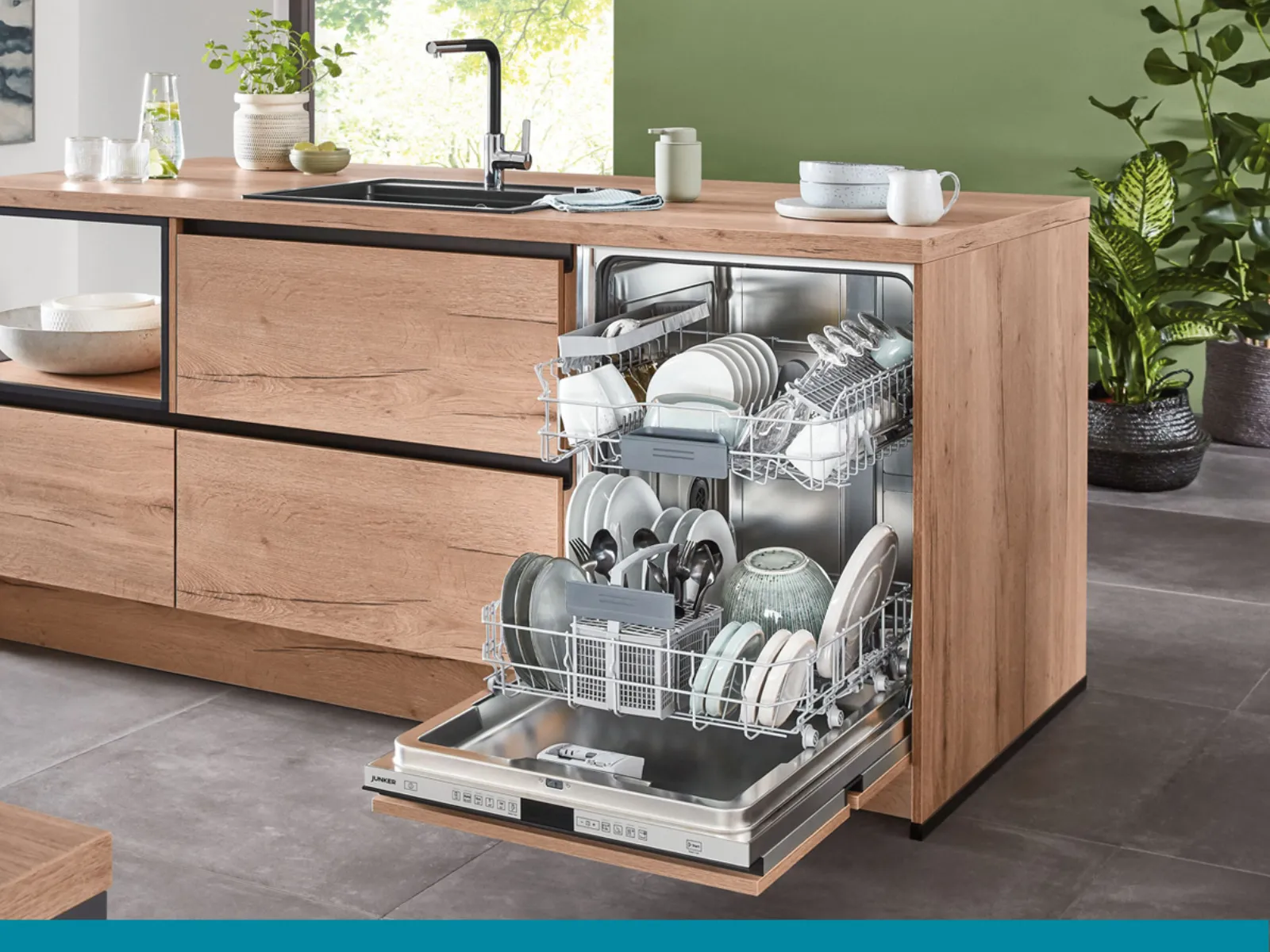 Une cuisine moderne avec un îlot en bois, un lave-vaisselle ouvert rempli de vaisselle propre, un évier et des plantes. 