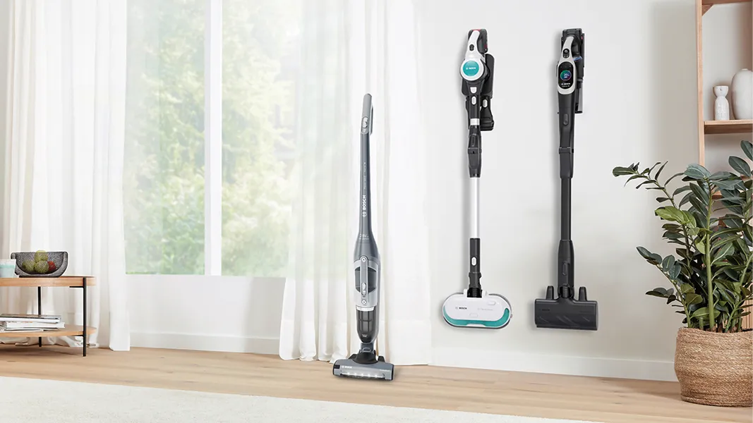 Drei Bosch‑Akkustaubsauger aufgereiht in einem hellen, modernen Wohnzimmer.
