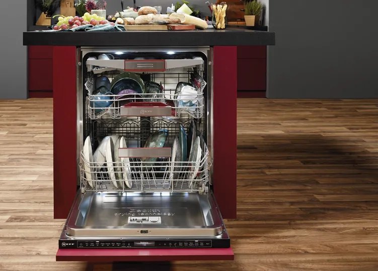 Ένα ανοιχτό πλυντήριο πιάτων σχεδόν γεμάτο με άπλυτα.