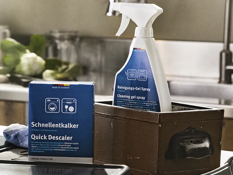 Καθαριστικά NEFF μέσα σε καγέ κουτιά άνω στον πάγκο  της κουζίνας.