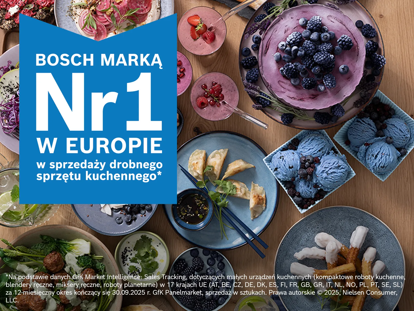 Asortyment kolorowych dań, w tym deserów i sałatek, ułożonych na drewnianym stole z nałożonym logo marki. 