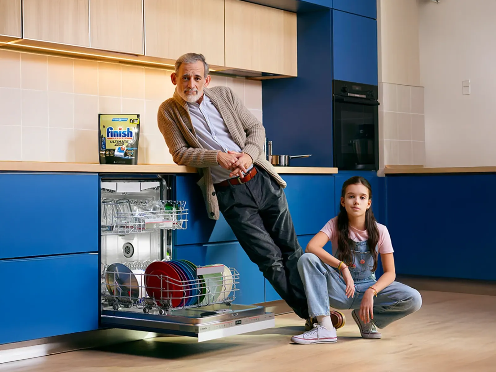 avô e neta numa cozinha com a máquina de lavar loiça aberta