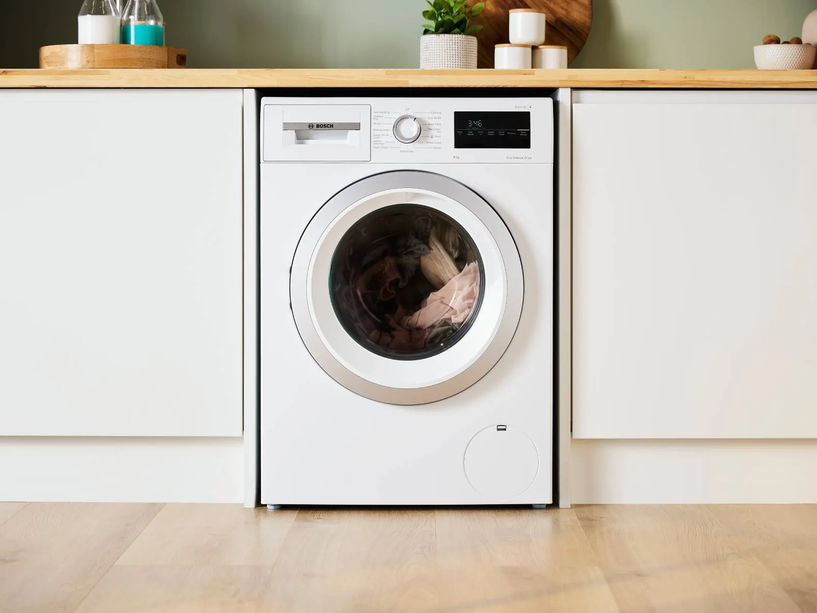 A white washing machine sitting on top of a wooden floor