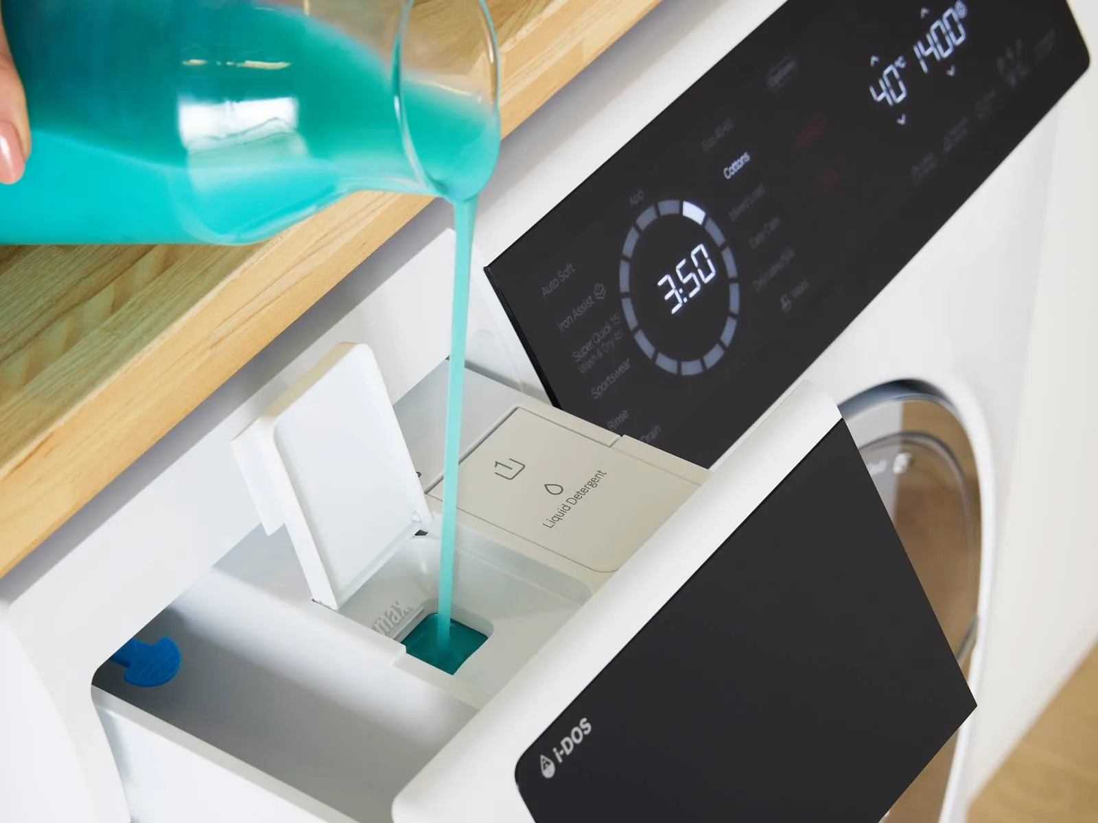 A close-up of a Bosch washing machine's detergent drawer, with blue liquid being poured in.