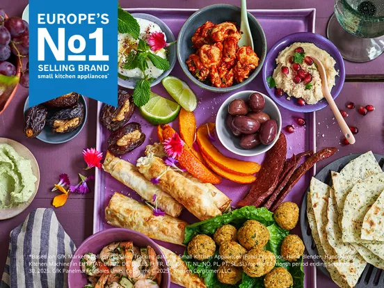 Europa's nummer 1 merk voor voedselbereidingsapparatuur, tentoon gesteld boven een tafel gevuld met levendige gerechten, desserts en dranken.