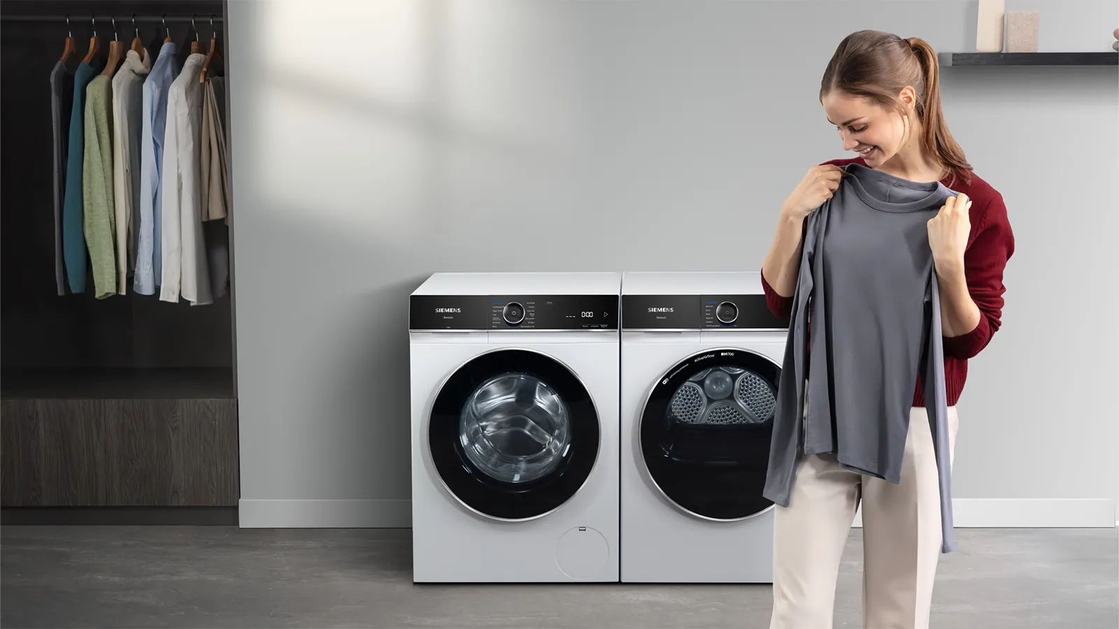 A modern laundry room with a washer and dryer, a lamp, and a shelf with plants.