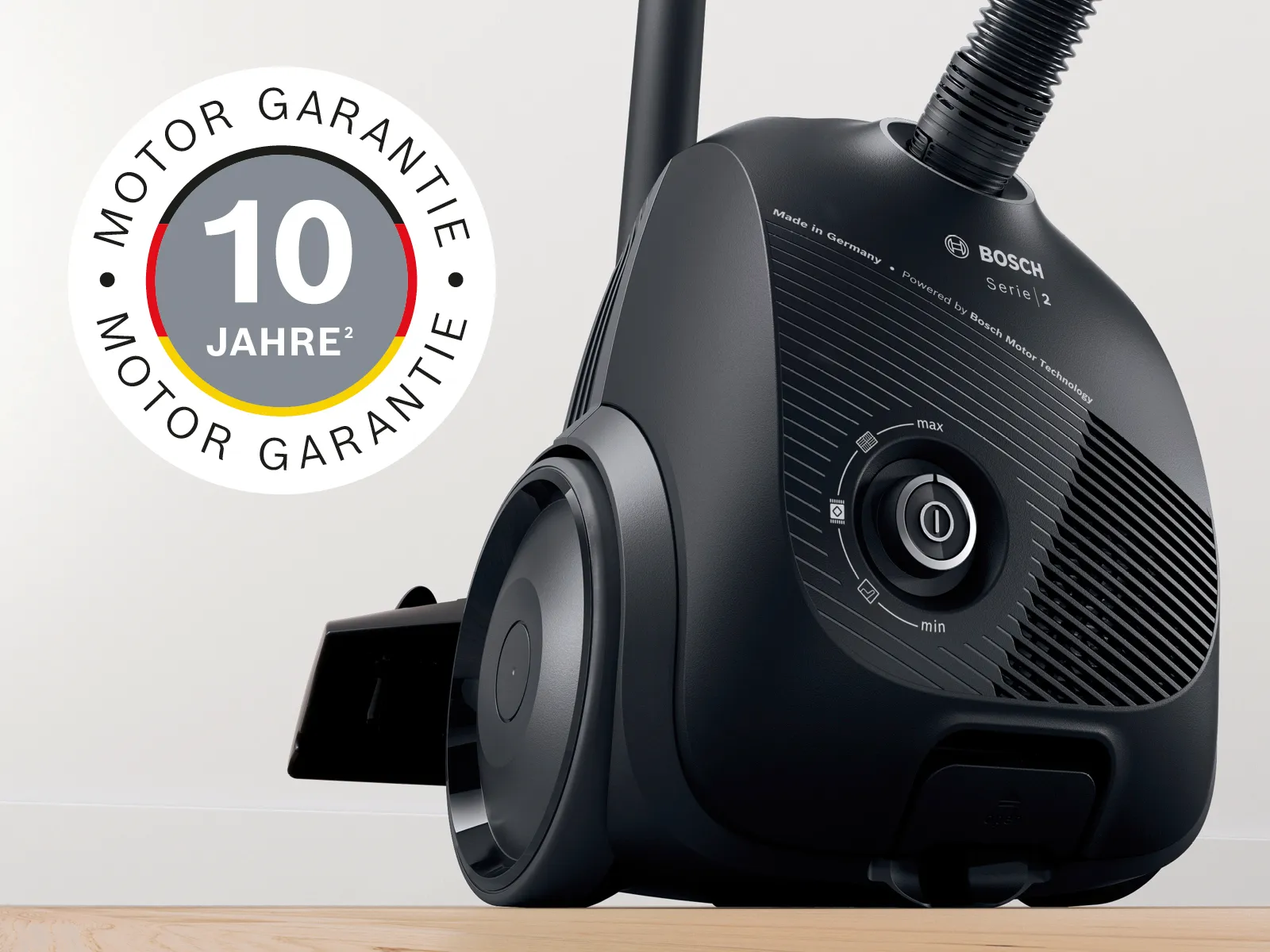 Ein schwarzer Bosch Staubsauger mit 10 Jahre Motorgarantie steht auf einem Holzboden.