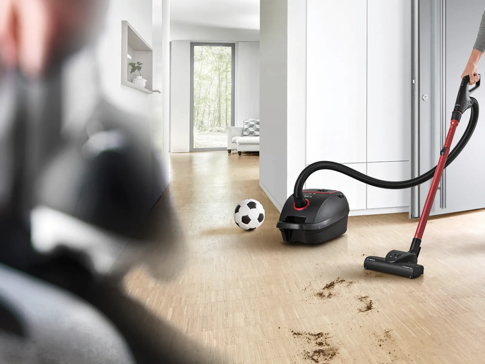 Eine Person reinigt einen stark verschmutzten Boden mit einem Bosch ProPower Staubsauger.