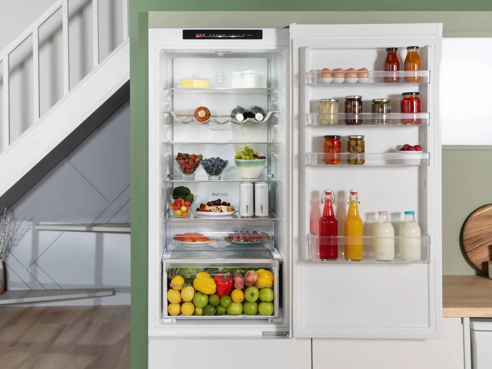 Open refrigerator with glass shelves, featuring Bosch branding, showcasing modern design and ample storage space.