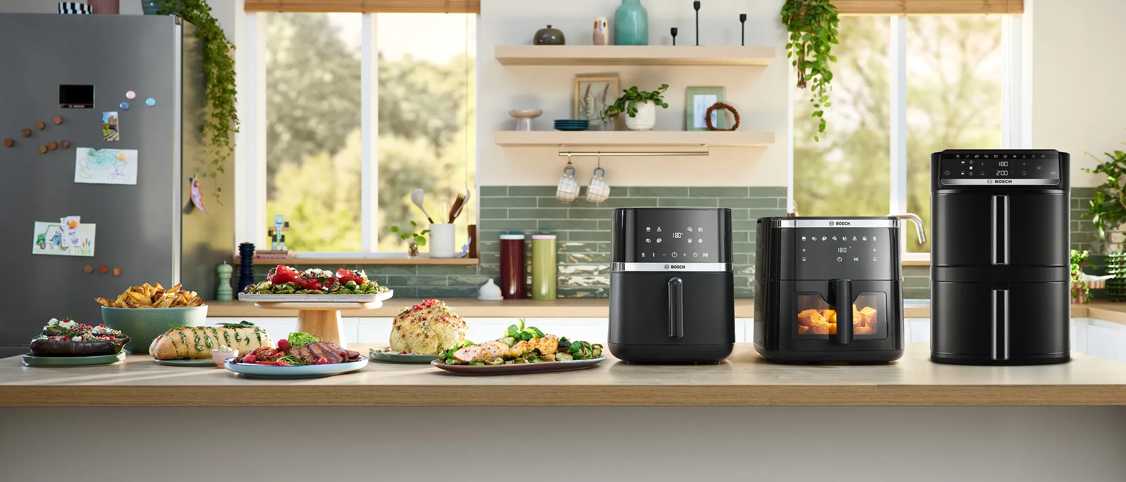 Three Bosch Air Fryers standing on a kitchen counter with various dishes next to it.