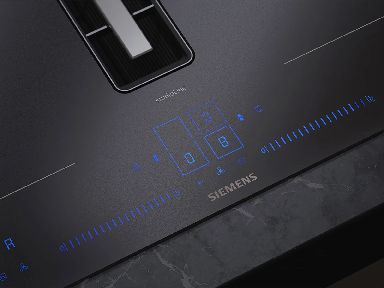 A close-up of a black Siemens studioLine induction cooktop with blue illuminated digital touch controls and a visible part of its integrated downdraft extractor.