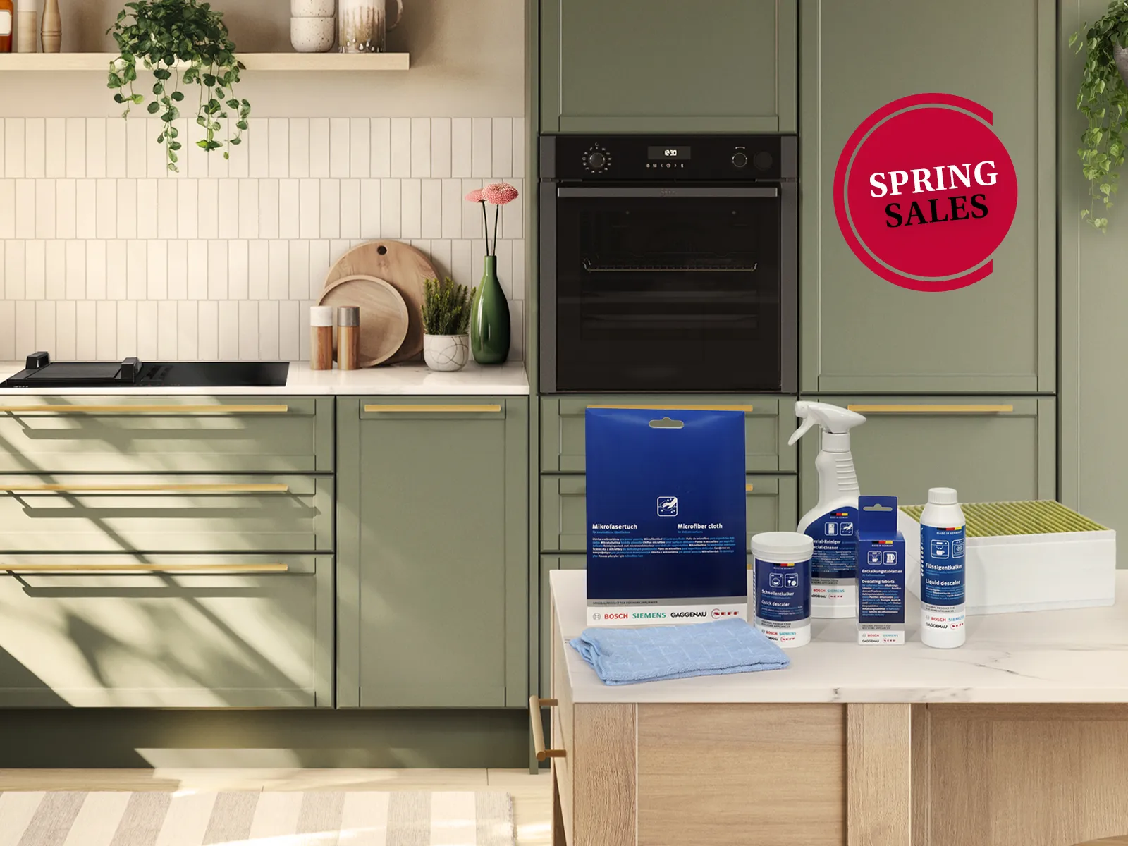 Modern kitchen with green cabinets, white countertop, cleaning products on island, hanging plants, fresh flowers, and a "Spring Sales" sign.
