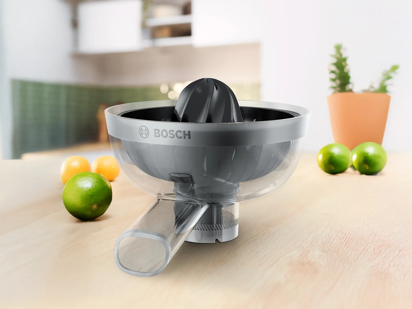 A Bosch citrus juicer on a wooden countertop, surrounded by fresh limes and lemons, against a bright kitchen background. 