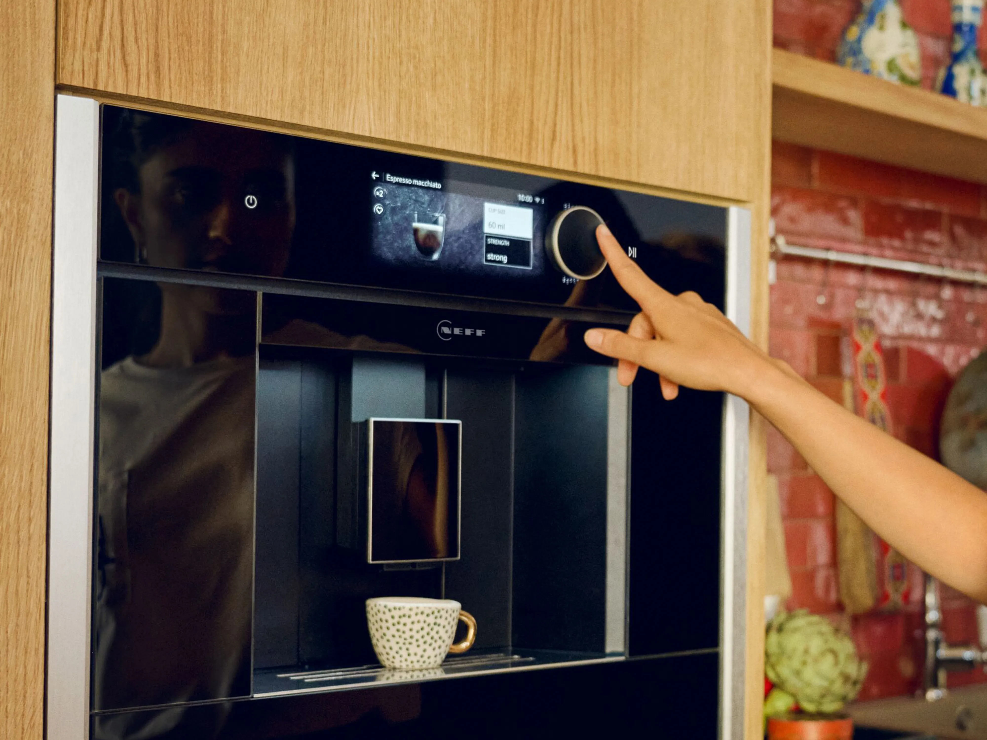 Integreeritud NEFF kohvimasin valmistab cappuccinot modernses köögis, kus on puidust kapid.