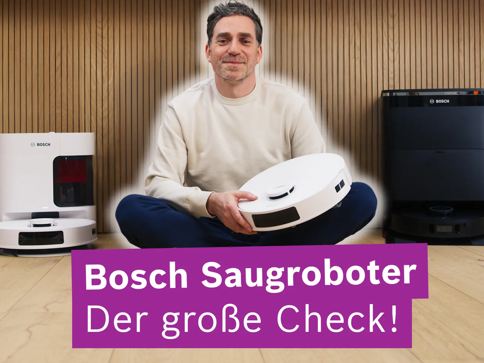 Bild von einem Mann, der auf einem Holzboden sitzt und die Bosch Saugroboter Modelle präsentiert.