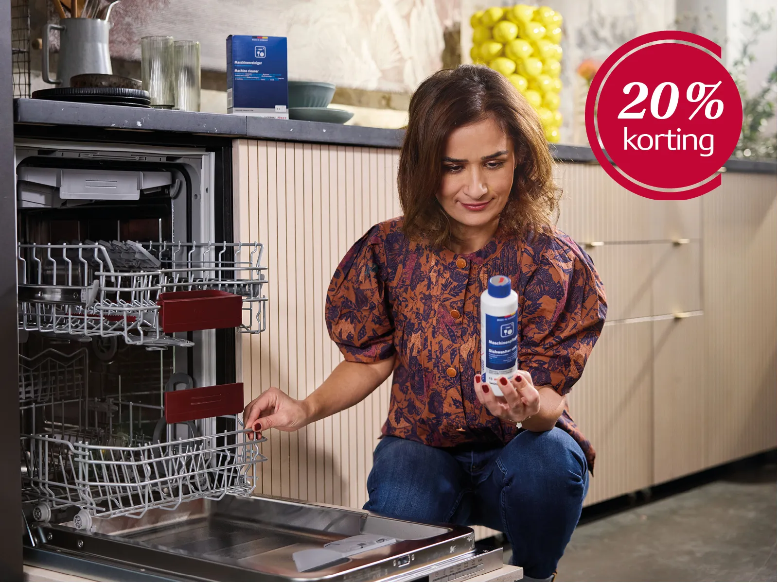 Dame zitten voor een geopende vaatwasser met reinigingsmiddel