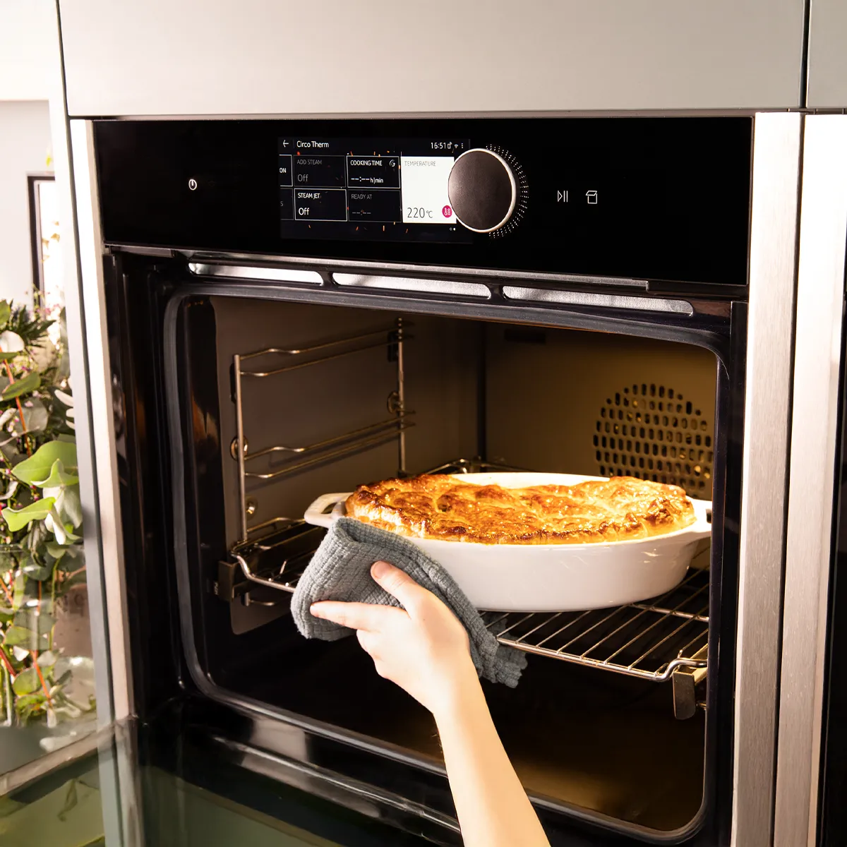 Oven with baked dish, hand removing dish, kitchen appliance, cooking, food preparation.