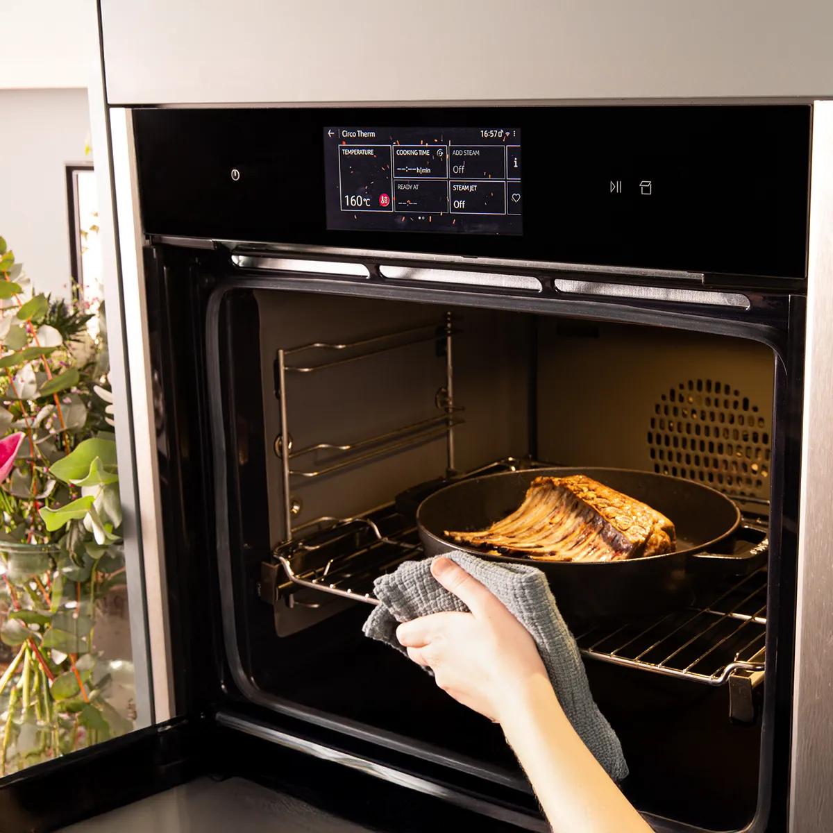 Backofen mit gebackenem Lebensmittel, eine Hand greift hinein, Küchengerät, Kochen, Zubereitung von Speisen.