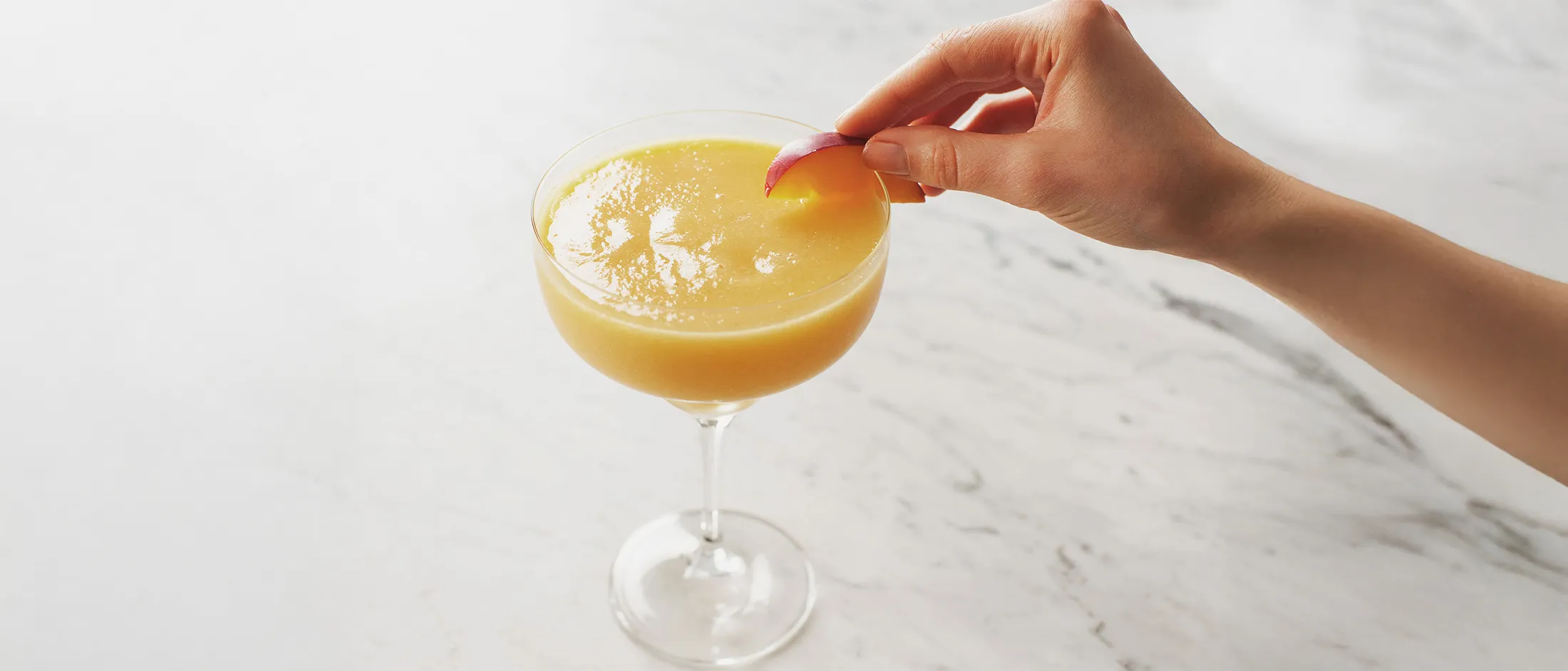 Placing peach slice on coupe rim, frozen peach now.