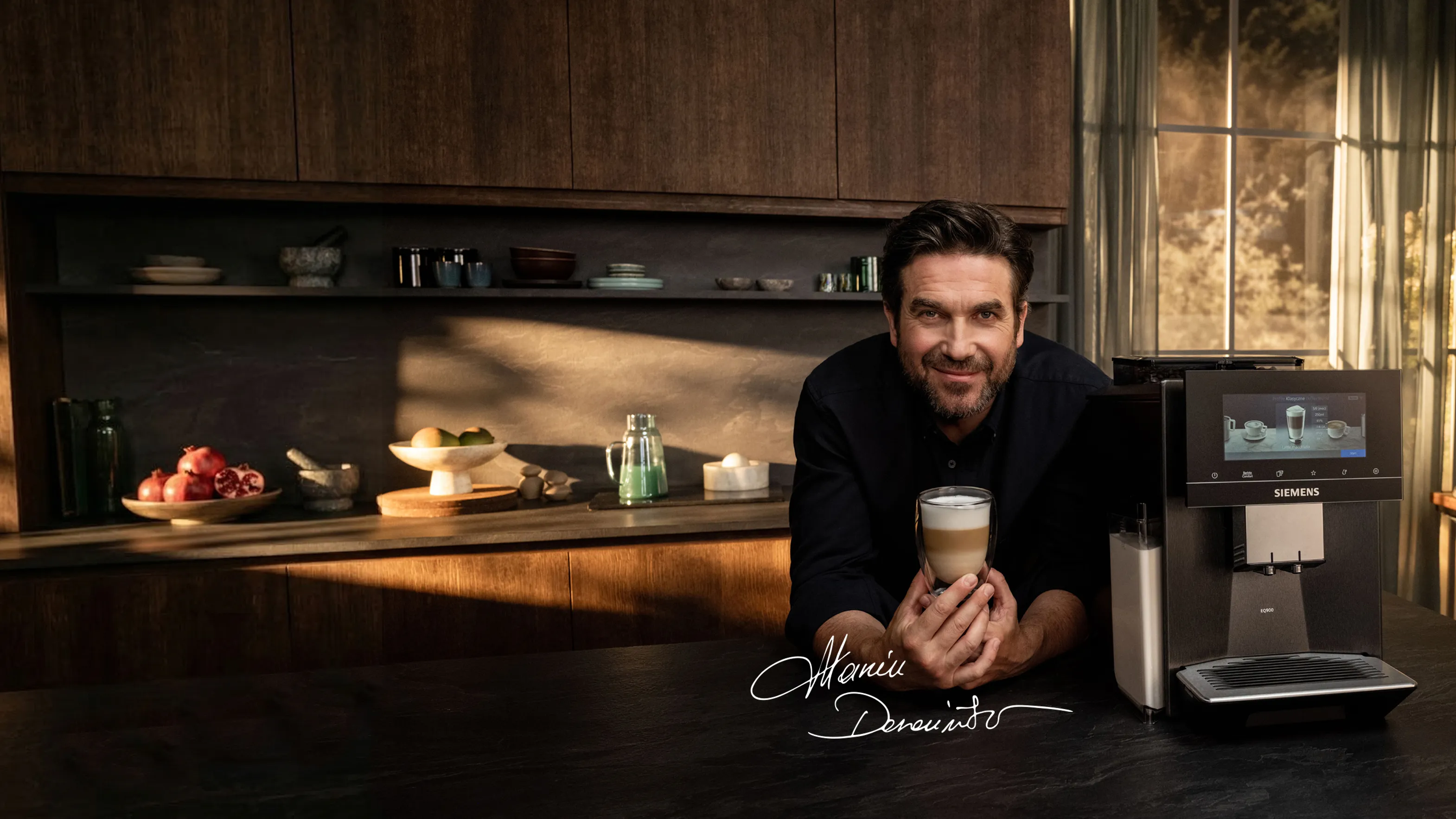 Mężczyzna trzyka filizanke kawy opierając się o ekspres