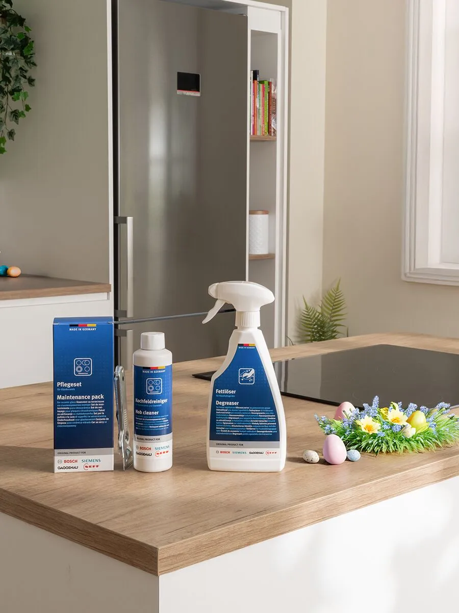 Bancada da cozinha com produtos de manutenção, juntamente com uma decoração floral de Páscoa com ovos pintados.