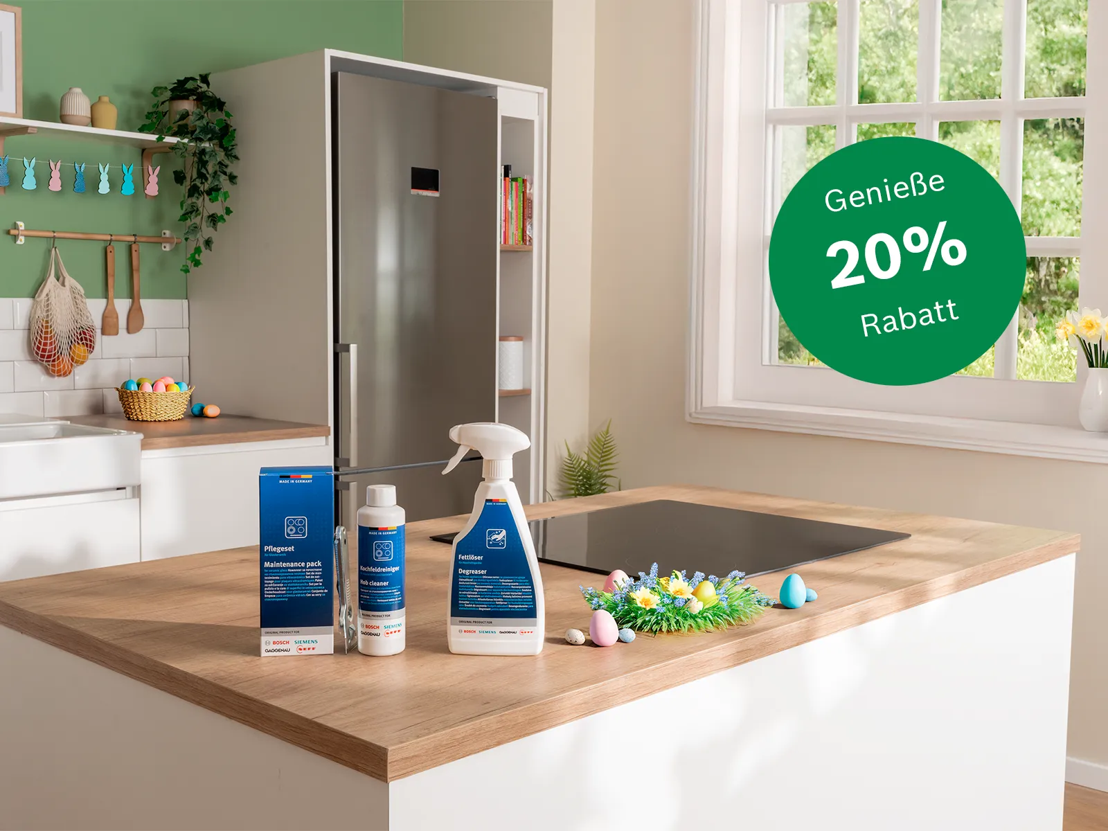 Helle Kücheninsel mit blauen Putzflaschen und Spray, Induktionsfeld, Ostereiern, Kranz, Spüle, Fenster mit Narzissen