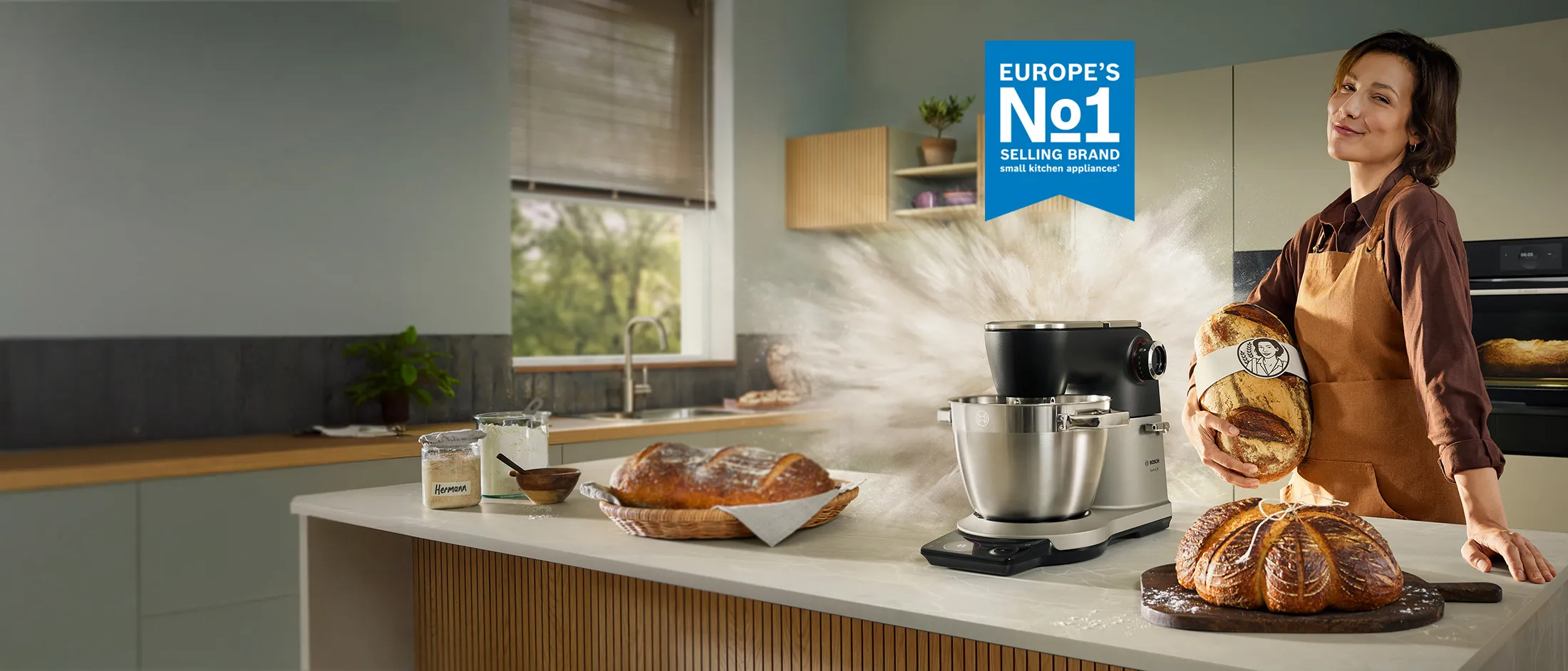 Ženska osoba u kuhinji sa kruhom u ruci i ispred nje se nalazi kuhinjski robot serie 8.