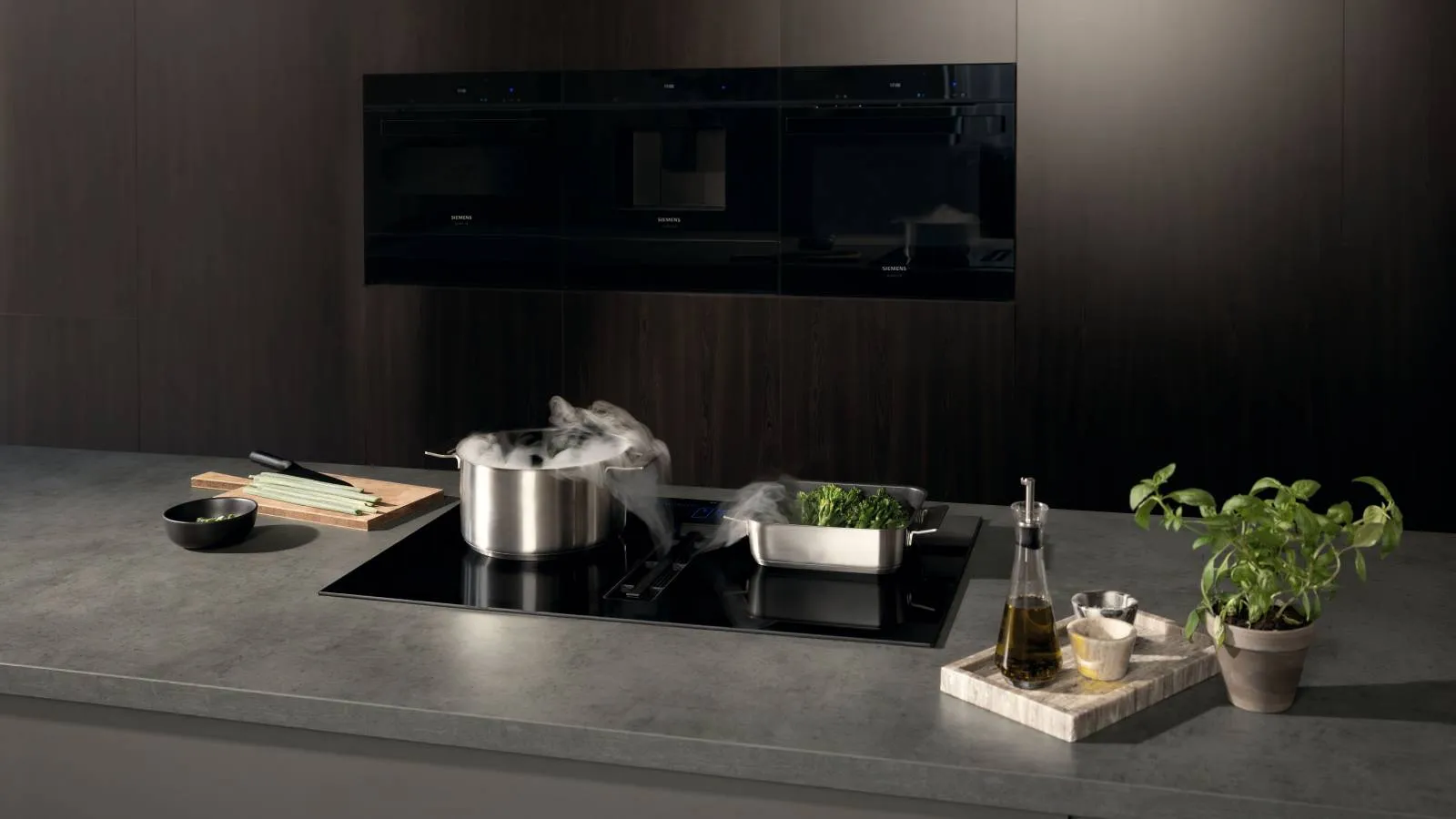Modern Siemens kitchen with a steaming pot on an induction cooktop, fresh vegetables, and cooking ingredients on the counter.