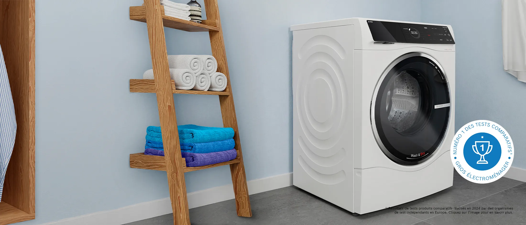 Un lave-linge et sèche-linge se tenant dans une salle de lavage lumineuse à côté d'une armoire ouverte contenant des chemises fraîchement lavées.