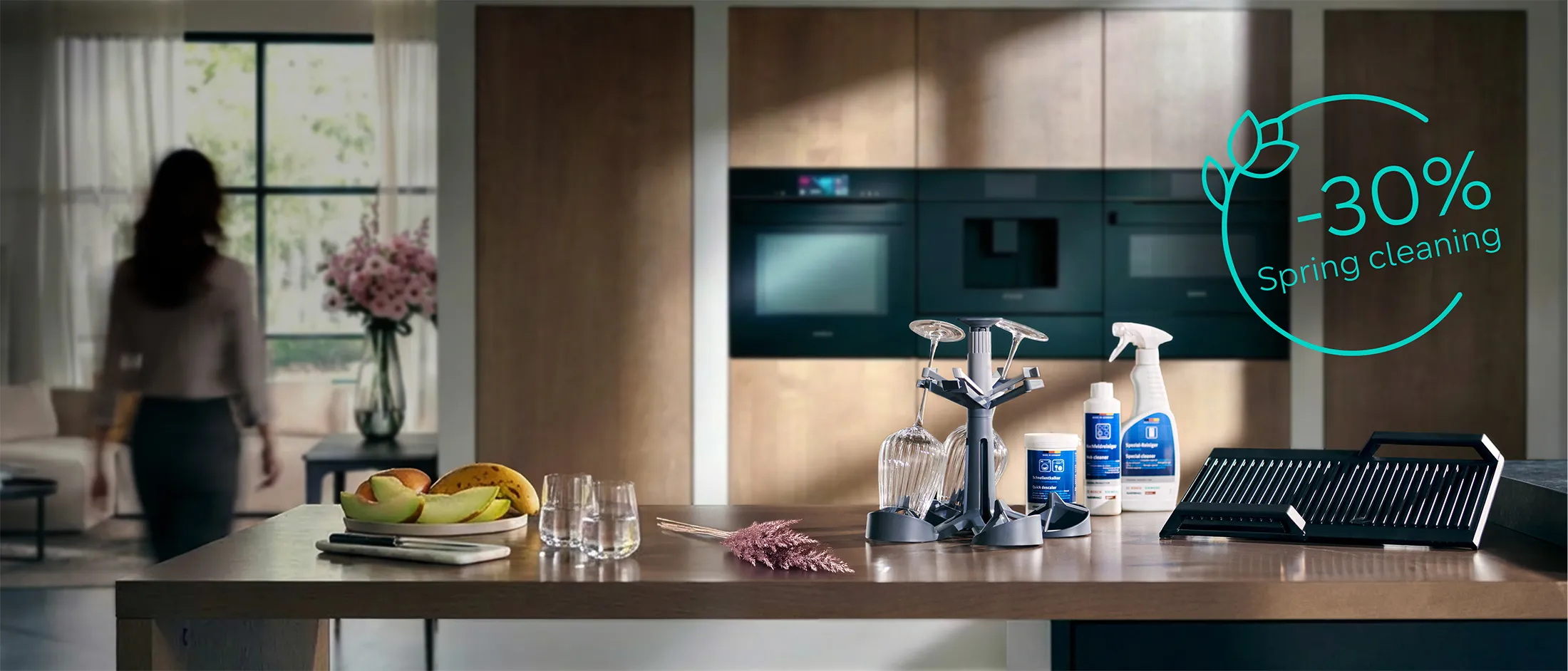 På en køkkenø i et moderne køkken er der udstillet tilbehør til opvaskemaskine og rengøringsprodukter. Billedet har teksten "-30 % Spring cleaning".