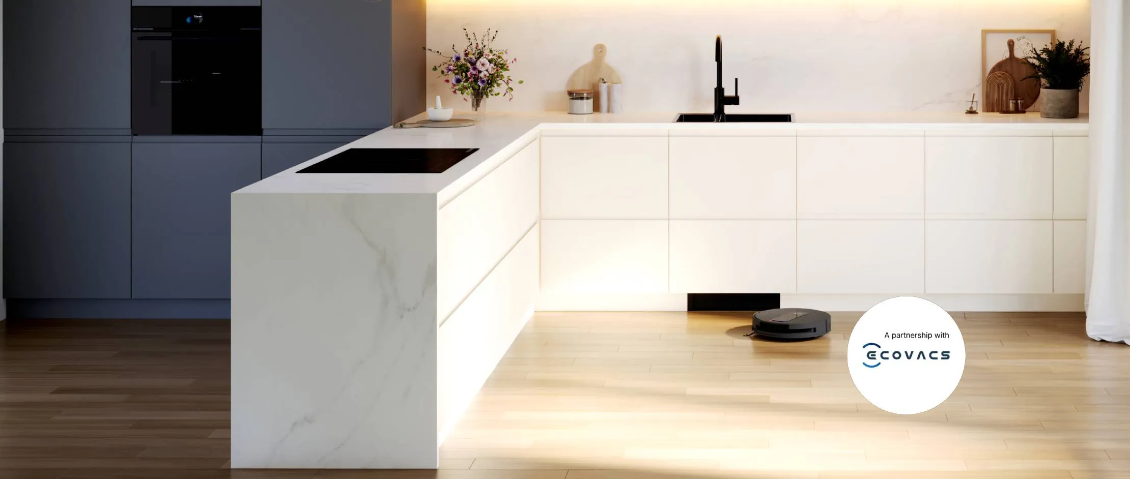 Cucina moderna minimalista con mobili bianchi e grigi, ripiani in legno, lampade a sospensione e un robot aspirapolvere su un pavimento in legno chiaro.