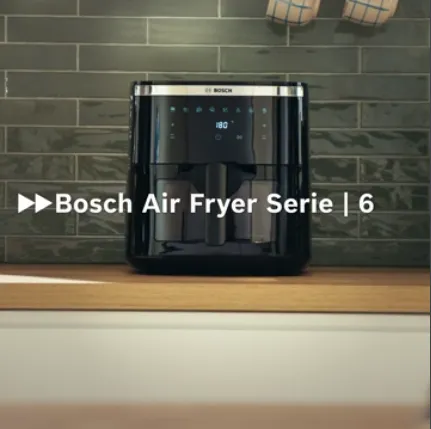 Bosch Air Fryer Series 6, elegant svart design, placerad på en köksbänk i trä med grönt kaklat stänkskydd.
