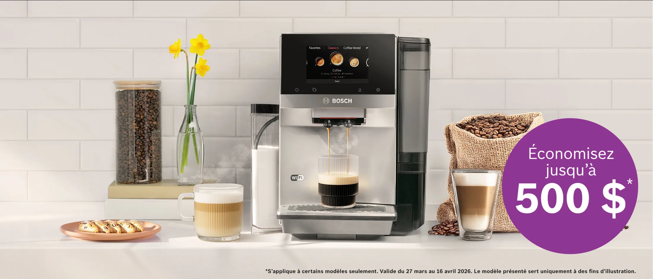 Une machine à café Bosch préparant un espresso avec de la mousse de lait, des grains de café dans un bocal et dans un sac, un latte, des croissants et des jonquilles posés sur un plan de travail de cuisine blanc.