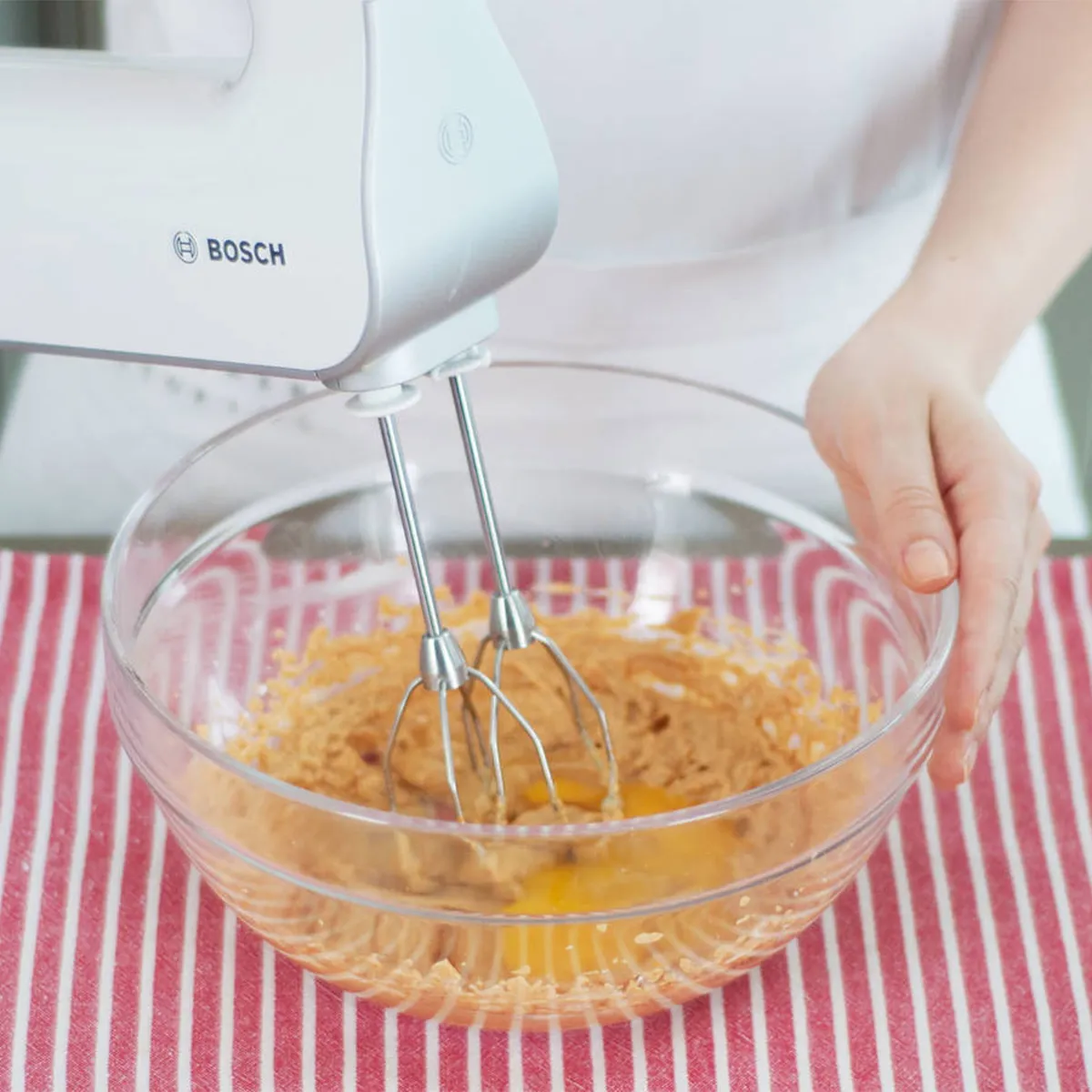 Person beating cream cheese, pumpkin, egg, sugar, and spices until smooth and combined for brownie topping