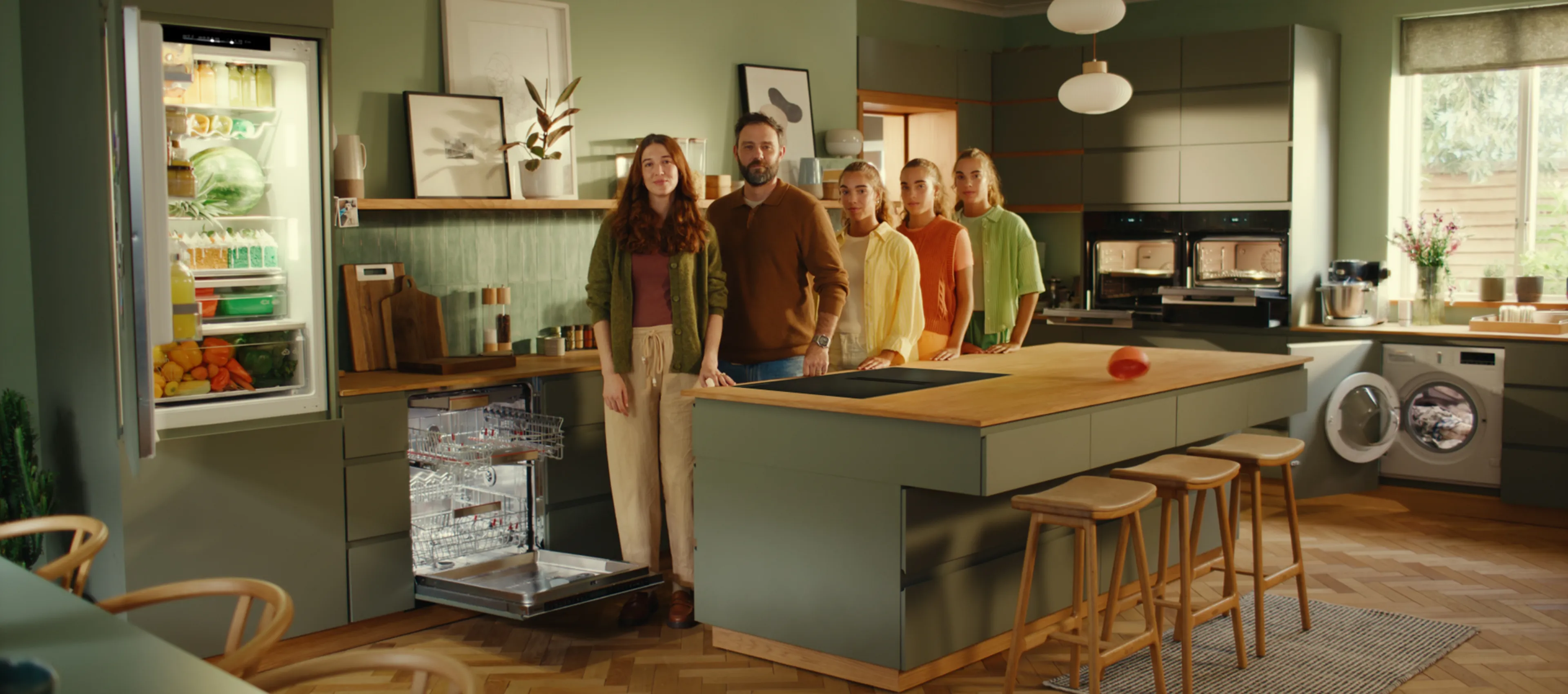Familia formada por una pareja y tres hijas en una cocina integrada con electrodomésticos Bosch