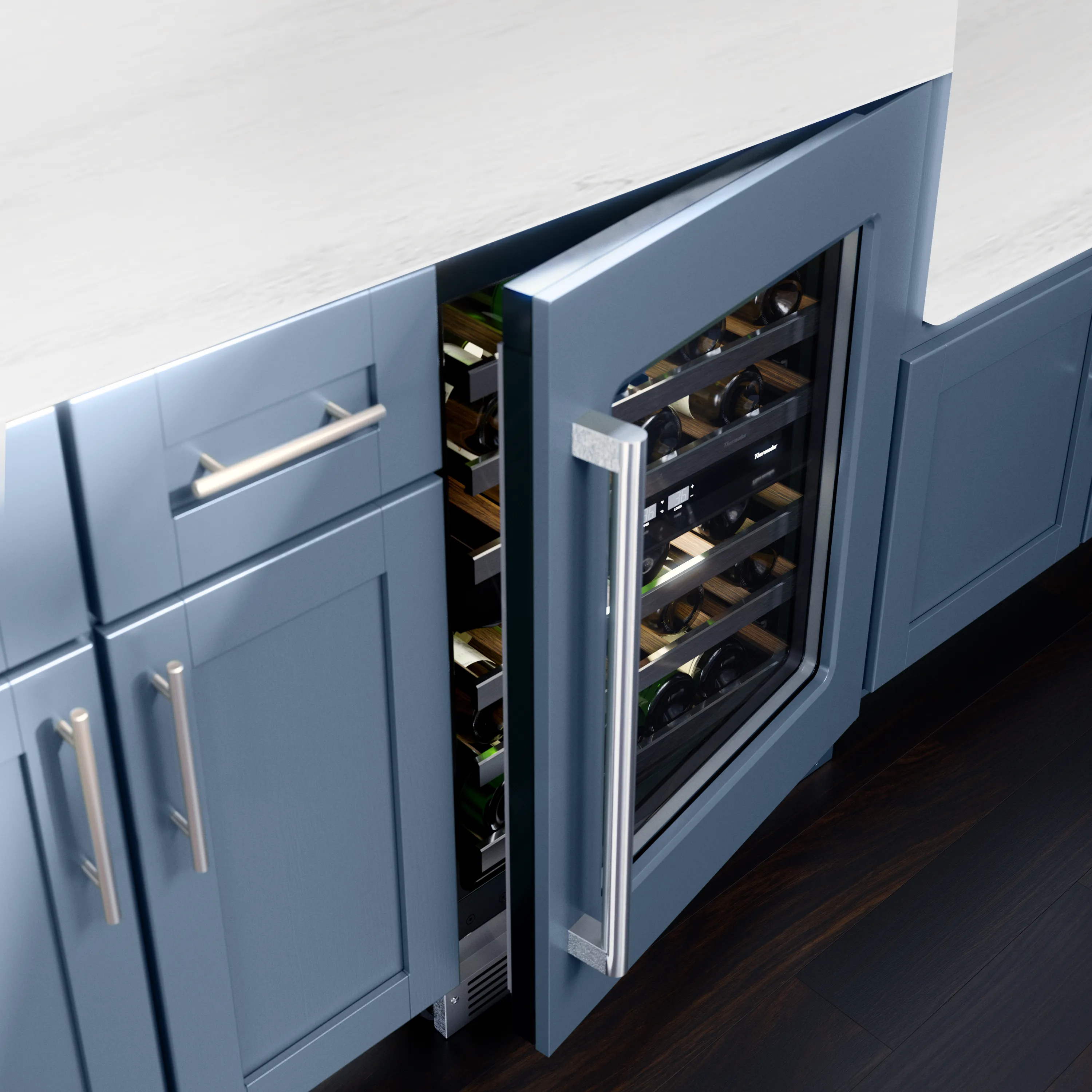 Under-counter wine refrigerator with a glass door ajar, showing horizontal bottles on wooden racks inside blue shaker-style kitchen cabinets with a stainless steel handle and dark hardwood floor.
