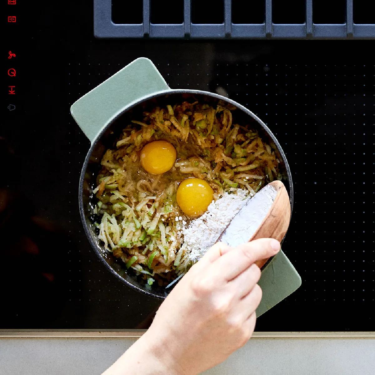 Cucina con uova strapazzate, verdure e utensili da cucina su una stufa.