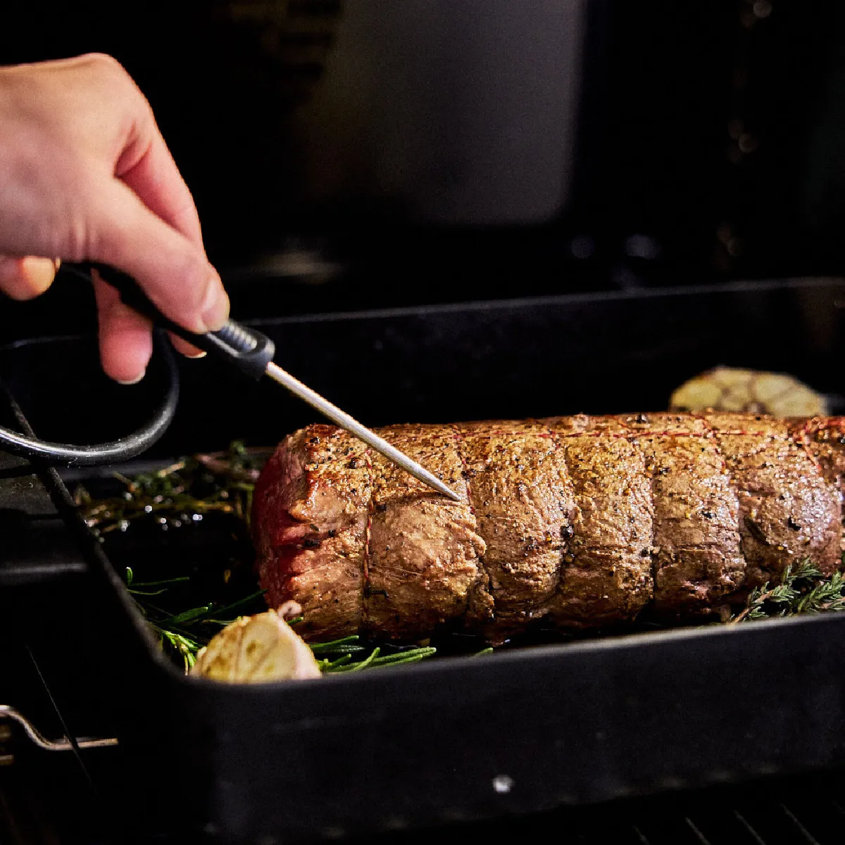 Piatto di carne arrosto preparato in forno, con presa a mano utensile per crogiolare o controllare il cibo.