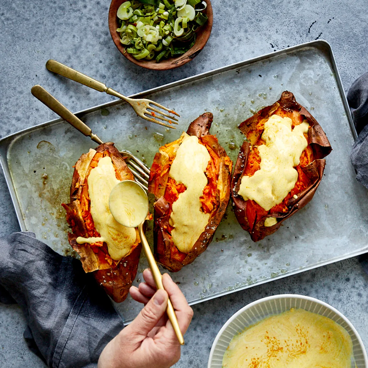 Patate al forno con topping, insalata e salsa di immersione su uno sfondo grigio.